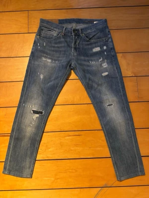 Dondup George Jeans W33 – Sällsynt Tvätt & Fint Skick - Dondup George jeans i snygg blå tvätt. En av Dondups mest eftertraktade modeller med riktigt bra passform och stretch för hög komfort.  Storlek: W33  Mått: • Midja (liggande): 42 cm • Ytterlängd: 92cm  Jeansen är i väldigt fint skick och har snygga detaljer som ger dem en exklusiv look. Perfekta till både vardag och mer uppklädda outfits.  Nypris flera tusen kronor.  Skriv gärna vid frågor eller om du vill ha fler bilder eller mått.