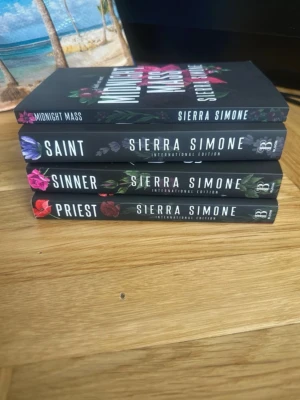 Sierra Simone - Priest-serien (4 böcker) - Fyra engelska pocketböcker av Sierra Simone: 'Priest', 'Sinner', 'Saint' och 'Midnight Mass'. Svarta omslag med färgstarka blommor och tydliga titlar på ryggen. Serien är känd för sina romantiska och dramatiska teman. Perfekt för dig som gillar intensiv skönlitteratur.
