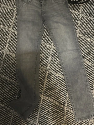 Grå slim fit jeans Jack & Jones - Snygga grå slim fit jeans från Jack & Jones, modell Glenn. Klassisk femficksdesign med dragkedjegylf och bälteshällor. Perfekta till en avslappnad streetwear-look och passar till det mesta. Materialet är mjukt och stretchigt för extra komfort.