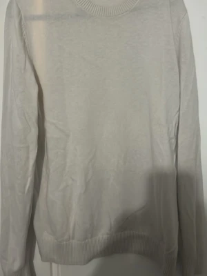 Beige stickad tröja Massimo Dutti - Snygg beige stickad tröja från Massimo Dutti i mjuk bomull. Tröjan har rund halsringning och ribbade muddar vid ärmslut och nederkant. Enkel och stilren design som passar till det mesta.