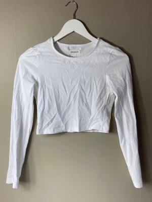 Vit croppad långärmad topp - Säljer en enkel och stilren vit croppad topp från even&odd (köpt på zalando). Toppen har långa ärmar och rund halsringning. Perfekt att matcha med höga jeans eller kjol. Passar mig som har storlek S.