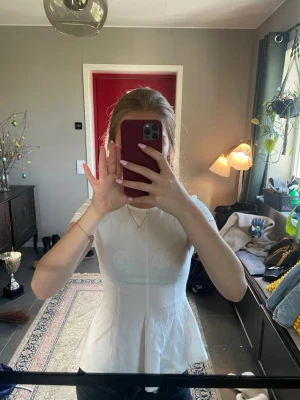 Vit peplum topp med kort ärm - Snygg vit topp med peplumskärning och korta ärmar. Toppen har en figurnära passform och rund halsringning. Aldrig använt. Skriv om ni har frågor💕