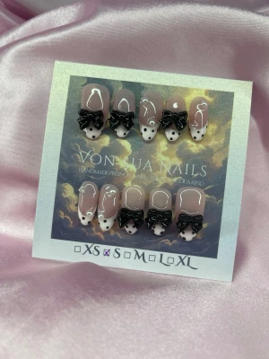 MuseNoir (S);Medium Almond - Handgjorda press-on naglar i nude med handmålad ljusrosa french, svarta prickar och svarta 3D-rosetter. Naglarna har en medium lång almondform och dekoreras med svarta prickar för en unik look. Perfekt för dig som vill ha något extra till naglarna. S: 15 mm, 11,5 mm, 12 mm, 11 mm, 9 mm 