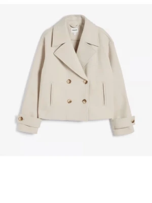 Beige skepparkavaj från Mango - Stilren beige skepparkavaj från kappal med dubbelknäppning och breda slag. Jackan har två fickor framtill och dekorativa knappar vid ärmsluten. Tillverkad i ett mjukt material som ger en lyxig känsla och passar perfekt till höstens och vinterns outfits.