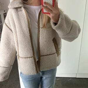 Beige teddyjacka med dragkedja - Säljer världens snyggaste teddyjacka med mjukt, fluffigt material och bruna detaljer längs dragkedja och sömmar. 🐑⭐️ Storlek: M ❣️ Om du har några frågor så är det bara att fråga 😊