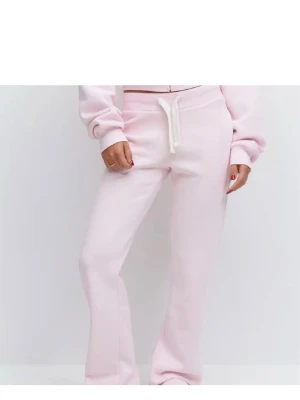 Rosa mjukis byxor - Säljer ett par ljusrosa mjukisbyxor med raka ben och vit dragsko i midjan. Byxorna har en avslappnad passform och är tillverkade i mjukt sweatshirtmaterial som känns skönt mot huden. Perfekta för chill dagar eller när du vill vara extra bekväm.