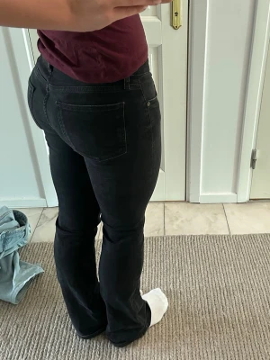 Svarta bootcut jeans med stretch - Säljer ett par bootcut jeans med stretchig passform. De är svarta med en liten urtvättad look. Jeansen är midrise och är i ett mjukt, bekvämt material som sitter snyggt. Knappast använda.