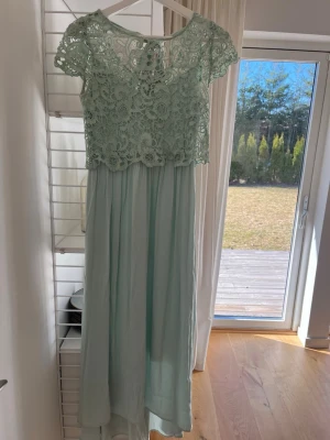 Ljusgrön långklänning med spets - Söt ljusgrön långklänning med spets och korta ärmar & knyte i nacken. Tyvärr för liten för mig så har inte kommit till användning💕