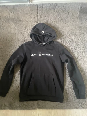  Hoodie Sail Racing - Säljer en svart hoodie från Sail Racing. Använd ett par gånger, köpt för 799kr. Storlek 170 passar typ S. 