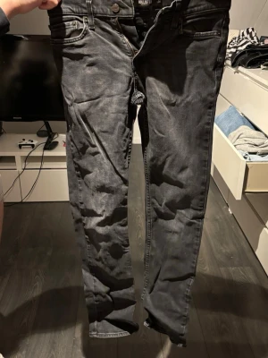 Grå slim fit jeans från Hollister - Säljer ett par grå slim fit jeans från Hollister med klassisk femficksdesign och knappgylf. Jeansen har en snygg tvättad look och raka ben. Perfekta för dig som gillar en stilren och avslappnad vibe.