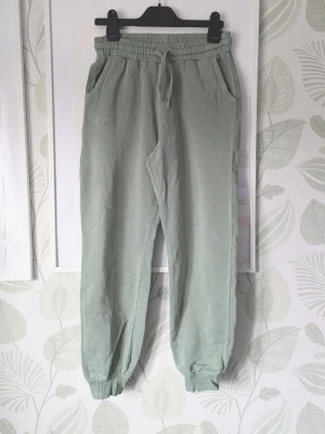 Byxor KappAhl Storlek 146-152 - Storlek 146 passar även storlek 152. - I fint skick . - Exakta färgen är väldigt svår att få på bilden det är en fin grön färg. - Tyget är i bra skick någon svag fettfläck syns på ben se extrabilder. - Lite skav i metalldelar i midjesnöre. - Lite lite ljusare i tyg jämfört med ny som kan synas lite i tex kanter. - Jag kan ha missat någon miniskavank men jag har försökt att granska plagget så gott det går.