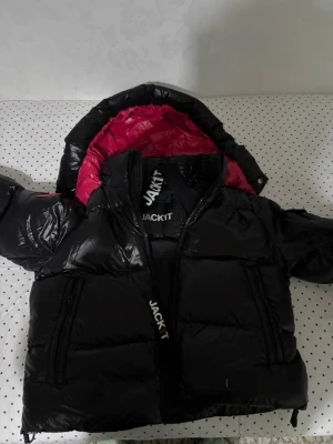 Svart pufferjacka från Jackit - Säljer en svart pufferjacka från Jackit med cool rosa insida och matchande rosa patch på ärmen. Jag köpte jackan för 2500 nypris och säljer den för detta priset. Vid snabbköp var gärna säkra och prisförslag är alltid välkomna 