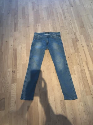 Replay anbass herr storlek 32/32 - Snygga blå slim fit jeans med lätt slitna detaljer och klassisk femficksdesign. Jeansen har normal midja och raka ben. Perfekta för en avslappnad och trendig look. Materialet är denim i bomull.