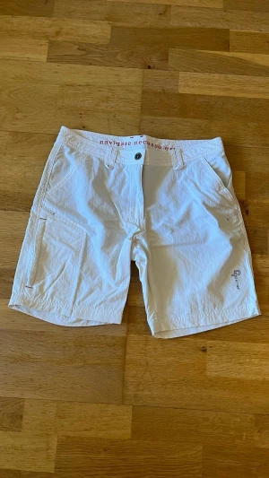 Vita shorts från Pelle P - Snygga vita shorts från Pelle P i mjuk bomull. Klassisk design med normal passform, bälteshällor och knappgylf. Shortsen har diskreta fickor fram och bak samt en liten broderad logga på ena benet. Perfekta för varma dagar. Bälte ingår.