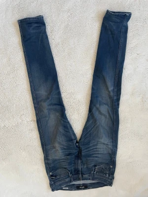 Replay Jeans - Säljer ett par blå jeans från replay med klassisk femficksmodell och dragkedjegylf och en tidlös passform. Jeansen har en snygg tvätt med slitningar. Perfekta för en trendig och avslappnad stil.