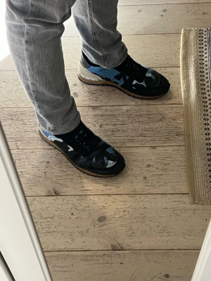 Valentino skor - Snygga skor från Valentino (rockrunners) med blå, svart och vit camo-mönstrad ovandel i textil och mocka. Perfekt för dig som vill sticka ut lite grann men behålla en clean och stilren ”look”. Skorna är i mycket bra skick och medkommer box, dustbag osv. Nypris 7000+. Pris kan diskuteras vid snabb affär. Självklart äkta👍