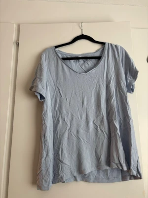 Ljusblå t-shirt med v-ringning - Enkel ljusblå t-shirt med v-ringad hals och korta ärmar. Känns skön mot huden. Perfekt till jeans eller shorts för en avslappnad look.