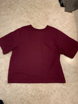 Vinröd t-shirt - En enkel vinröd t-shirt. T-shirten har rund halsringning och korta ärmar. Tillverkad i mjukt bomullstyg som känns skönt mot huden. Perfekt för en avslappnad och stilren look.