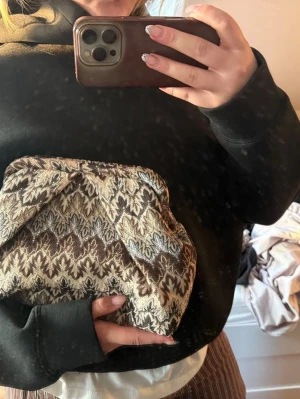 Mönstrad kuvertväska från bäcksöndergaard - Säljer en unik kuvertväska från bäcksöndergaard med ett snyggt etnoinspirerat mönster i beige, brunt och grått. Väskan har en mjuk, puffig form och är tillverkad i textilmaterial. Perfekt accessoar för att lyfta vilken outfit som helst!⭐️