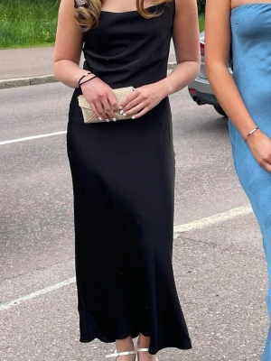 Balklänning från missäy💕 - Elegant svart långklänning med smala axelband och mjukt, följsamt tyg som ger en stilren siluett. Klänningen har en enkel, klassisk design och passar perfekt till speciella tillfällen. Matcha med klackar och accessoarer för en komplett look.