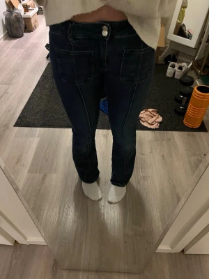Mörkblå jeans med bootcut - Säljer ett par mörkblå jeans med bootcut och markerade sömmar. Jeansen har två stora fickor framtill och stängs med knapp och dragkedja. Snygg och enkel modell som passar till det mesta. Materialet är klassisk denim. Perfekta nu till sommaren💝