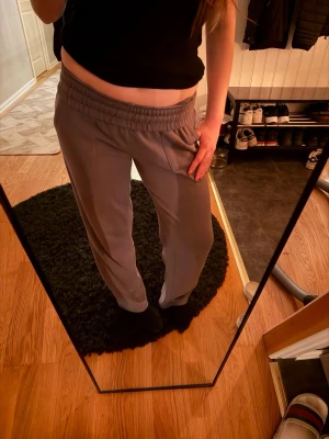 Grå mjukisbyxor med dragsko - Säljer ett par grå mjukisbyxor med bred resår i midjan och dragsko för extra komfort. Byxorna har raka ben och sidofickor, perfekta för chill dagar hemma eller när du vill vara bekväm. Materialet känns mjukt och följsamt.