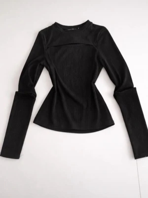 Svart ribbad långärmad topp - Snygg svart ribbad topp med lång ärm och figurnära passform. Toppen har en enkel, stilren design med rund halsringning och är perfekt för att skapa en clean look. Materialet är stretchigt och bekvämt, vilket gör den lätt att styla till olika outfits.