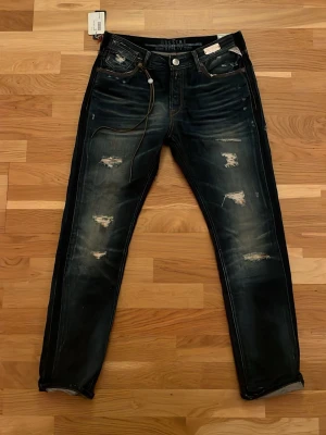 Replay Maestro slitna jeans blå - Säljer ett par helt nya mörkblå Replay Maestro jeans med alla orginal lappar kvar. De är aldrig använda. Jeansen har klassisk femficksmodell, orangea sömmar och är tillverkade i denim. Snygg vintagekänsla och handgjorda detaljer. Nypris ligger på 2300kr