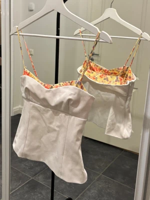Zara sommartopp - Topp från Zara, vit med en söt blommig kant på insidan. Sitter otroligt snyggt på, figursydd med dragkedja i sidan. Använd 1 gång, som ny. Stl S. (Lite skrynklig på bilden, fixar till bättre rättvis bild vid intresse!) 