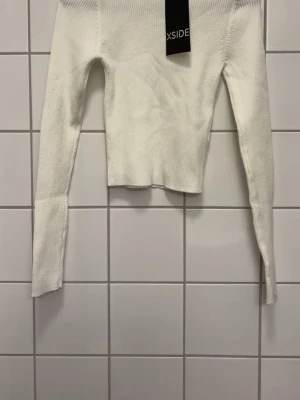 Vit ribbstickad tröja - Säljer en vit ribbstickad tröja med lång ärm och tight passform. Tröjan har en croppad modell och är tillverkad i mjukt, stretchigt material som passar perfekt till jeans eller kjol.