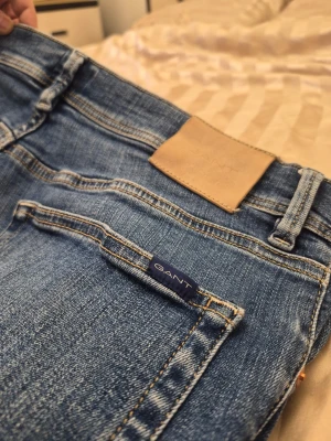 Gant Maxen extra slim fit blåa jeans, storlek W33/L32 - Säljer ett par klassiska blå jeans från GANT med raka ben och femficksmodell. Jeansen har snygga slitningar och kontrastsömmar, samt en liten GANT-logga på fickan. Tillverkade i slitstarkt denimtyg som passar perfekt till en avslappnad stil.
