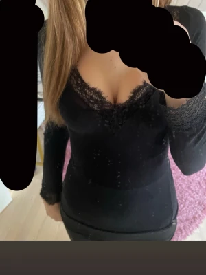 Svart intimissmi topp - Snygg svart långärmad topp med v-ringning och spetsdetaljer vid halsringning. Har en liten defekt.