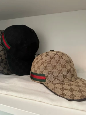 Gucci beige keps med GG-mönster - Helt ny beige keps från Gucci med klassiskt GG-monogram över hela kepsen och en grön-röd rand på sidan. För beställning så kan priset diskuteras och bli billigare, viktigt att ni skriver till mig. 💫