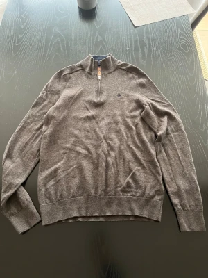 Grå halvzip-tröja från Morris  - Snygg brun långärmad tröja från Morris med halv dragkedja och liten broderad logga på bröstet. Tröjan har ribbade muddar och är tillverkad i mjukt material som känns skönt. Inte använd ångrade att jag köpte den 