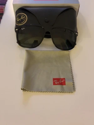Svarta Ray-Ban solglasögon - Klassiska svarta solglasögon från Ray-Ban med fyrkantig form. Kommer med originalfodral, putsduk och box. Snygg och tidlös design som passar till alla outfits. Som nya.