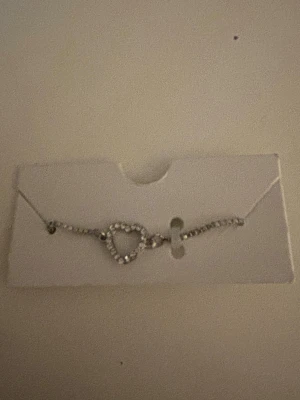 Silver armband  - Ett armband med hjärtformad detalj i silverfärg och glittrande stenar, helt oandvänd💕💕