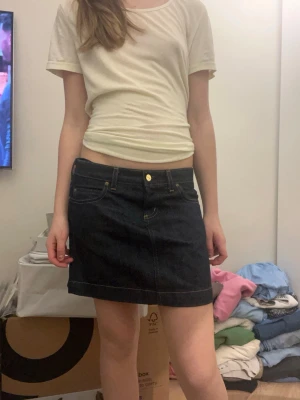 Mörkblå jeanskjol med fickor - Säljer en mörkblå jeanskjol med klassiska fickor fram och bak samt guldfärgad knapp och dragkedja. Jätte bra skick storlek XS/S 