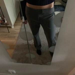 Low Waist kostymbyxor  - Jag säljer ett par Low Waist gråa kostymbyxor från Nelly. Dem är använda 1-2 ggr, är lite noppriga längst bak men inget man lägger märke till. För referens är jag 177cm och skulle säga att dem är något korta för mig. 2,3 lånade. Skriv vid frågor! 🌸