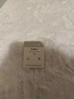 Glitter guldpläterade örhängen - Snygga örhängen från Glitter i sterling silver 925 med 18 karats guldplätering. Örhängena har en enkel och stilren design med rund form och liten detalj i mitten. Perfekta för dig som gillar minimalistiska accessoarer.