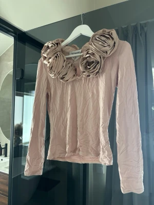 Beige långärmad topp med stora rosor - Supersnygg beige långärmad topp från Cottonade med stora tygrosor längs halsringningen. .