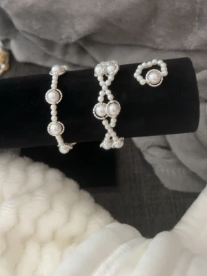 Sett med två armband en ring i vitt och silver - Ett sätt med två armband och en ring, alla gjorda i vita pärlor med silverdetaljer