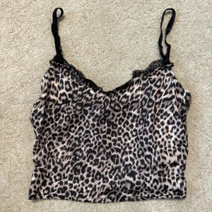 Leopardmönstrad linnetopp från SHEIN - Snygg leopardmönstrad linnetopp från SHEIN med tunna axelband och spetsdetalj vid urringningen. Toppen är croppad och gjord i mjuk polyester med lite stretch. Perfekt för dig som vill sticka ut med ett djurmönster!