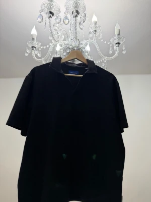 Svart  polotopp från jack&jones  - Cool svart polotopp från jack&jones med ribbad struktur och korta ärmar. Perfekt för dig som gillar en enkel men stilren look. Materialet är mjukt och bekvämt, och kragen ger en snygg touch till outfiten. L men passar M!!