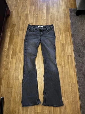 Grå bootcut jeans med rå kant - Snygga grå jeans med bootcut-modell och råa kanter nertill. Klassisk femficksdesign och låg midja. Jeansen har en avslappnad vibe och passar perfekt till sneakers eller boots. Materialet är denim i bomull med lite stretch för extra komfort.