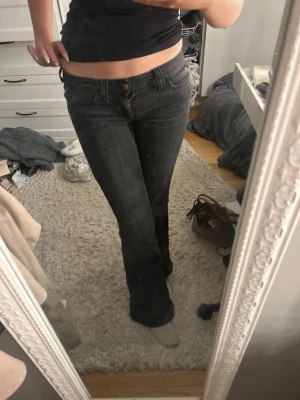 Cheap monday jeans - Säljer ett par mörkgrå bootcut jeans med låg midja och klassisk femficksmodell. Jeansen har en snygg tvätt och stängs med knapp och dragkedja. Perfekta för en avslappnad och trendig look.