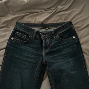 Mörkblå jeans med broderade bakfickor - Säljer ett par snygga mörkblå jeans i bra skick. 