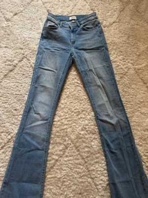 Blå bootcut jeans från Only - Snygga blå bootcut jeans från Only med klassisk femficksmodell och ljus tvätt. Jeansen har normal midja och utsvängda ben, vilket ger en retroinspirerad look. Tillverkade i mjukt denimtyg som sitter bekvämt hela dagen.