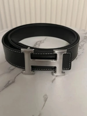 Svart bälte med silver logga - Bälte