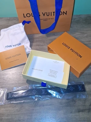 Louis Vuitton monogram armband svart - Snyggt armband från Louis Vuitton i svart läder med klassiskt monogrammönster och silverfärgat LV-spänne. Kommer med originalförpackning, dustbag och certifikat. Perfekt accessoar för dig som gillar exklusiv och tidlös design. Fantastiskt skick och bara använt ett fåtal gånger. Pris kan diskuteras😁😄