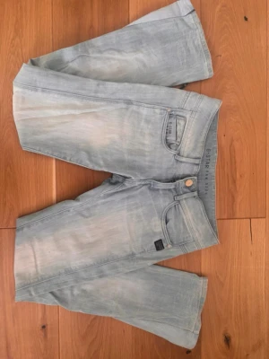 Ljusblå jeans från G-Star RAW - Säljer ett par ljusblå jeans från G-Star RAW med klassisk femficksmodell och snygga slitningar. Jeansen har en avslappnad passform och detaljer som metallknapp och logotypmärke vid fickan. Perfekta för en cool och avslappnad stil.